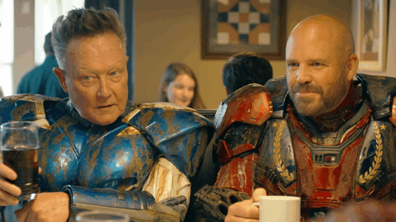 Blue Dragon (Robert Patrick) and Captain Triumph (David Denman) enjoy a post-kaiju breakfast with Peacemaker (John Cena) in Peacemaker Season 2 Episode 6 "Ignorance is Chris" (2025), DC Studios