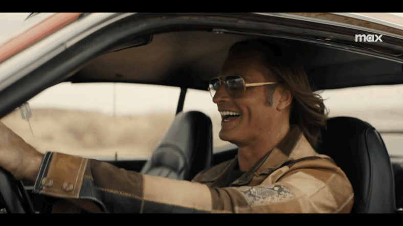 Jim Ellis (Josh Holloway) laughing while driving his muscle car in Duster Season 1 Episode 7 "K-129" (2025), Warner Bros. Television