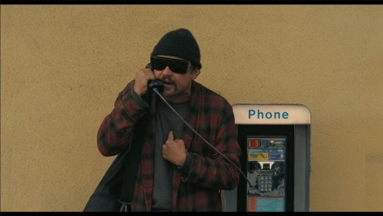 Rocketman/Bob Fergusson (Leonardo DiCaprio) attempts to contact the French 75 headquarters on a payphone in One Battle After Another (2025), Warner Bros. Pictures