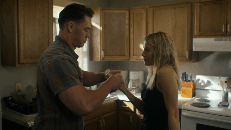 Christopher Smith (John Cena) helps Emilia Harcourt (Jennifer Holland) bandage her bloody knuckles in Peacemaker Season 2 Episode 1 "The Ties That Grind" (2025), DC Studios
