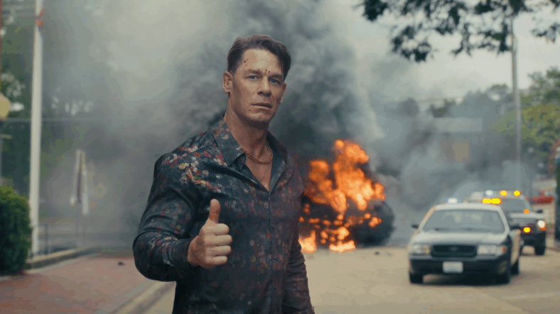 Peacemaker (John Cena) lets Harcourt (Jennifer Holland) know he's okay after stopping the Sons of Liberty in Peacemaker Season 2 Episode 3 "Another Rick Up My Sleeve" (2025), DC Studios