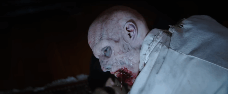 A zombie disturbed as it feasts in Resident Evil: Welcome to Raccoon City (2021), Sony Pictures Entertainment